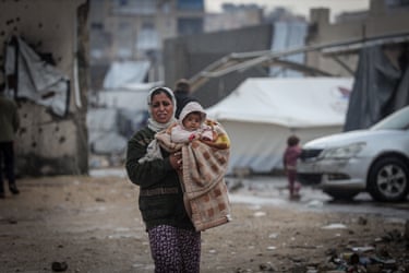 A woman walks through heavy rain with her child in Gaza