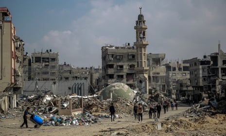 People walk amid debris of a mosque and buildings destroyed during Israeli strikes in Gaza City