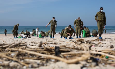 Israeli soldiers search for tar grains while cleaning Palmachim beach near the city of Rishon LeZion, Israel