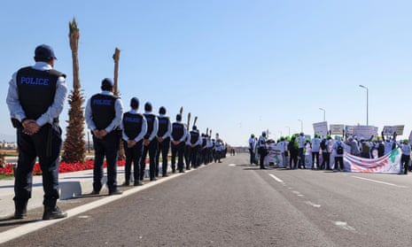 Police officers stand guard as the civil society group known as the Cop27 Coalition holds a march.
