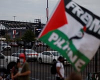 people standing outside stadium hold 'free palestine' flags