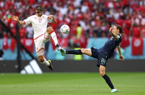 The masked Ellyes Skhiri of Tunisia jumps into a challenge with Jackson Irvine.