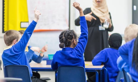 unidentifiable teacher in headscarf with primary children with hands up