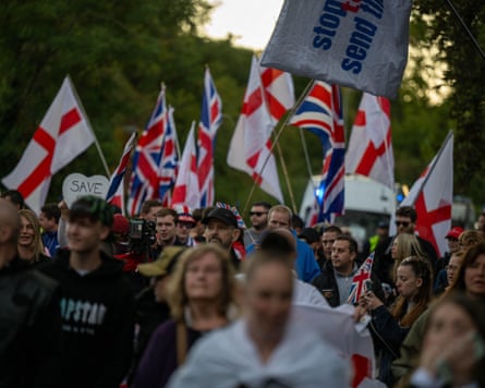 A crowd of people carrying English and UK flags