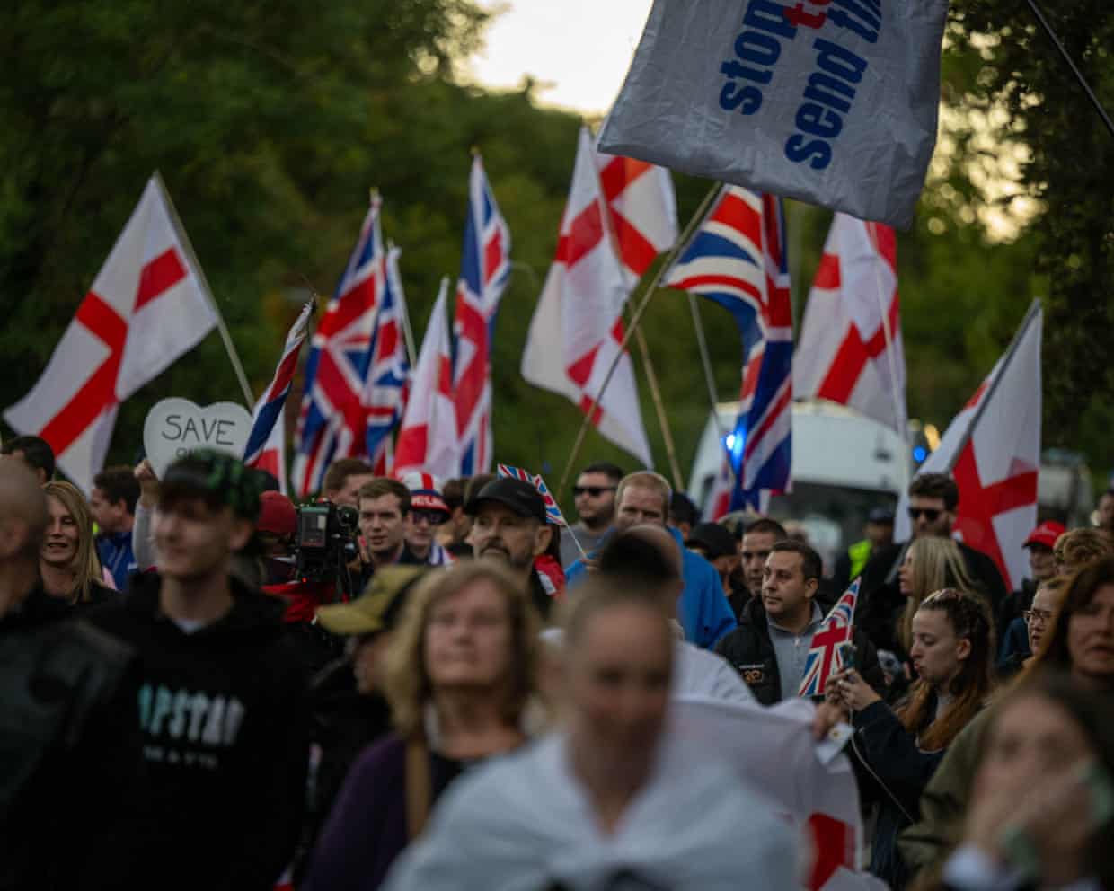 A crowd of people carrying English and UK flags
