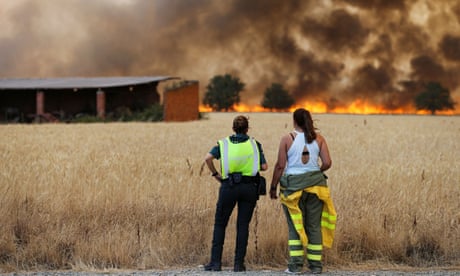 A guardia civil and a firefighter from the Brigadas de Refuerzo en Incendios Forestales watch as the fire reaches near Tabara, Zamora, July 2022
