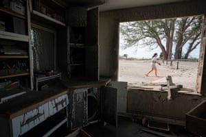 A woman walks near damaged beachside property