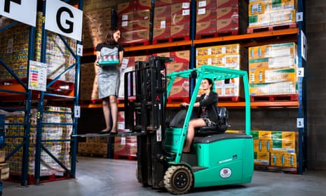 Iseult Ward standing on a forklift truck and Aoibheann O’Brien driving it in the FoodCloud warehouse in Dublin.