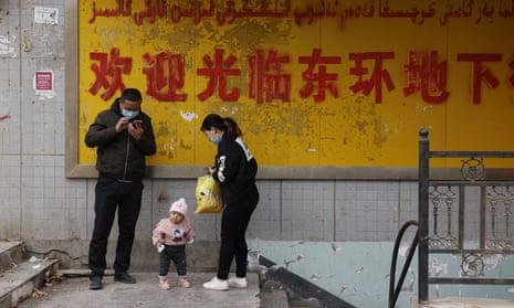 A family stands at the entrance to an underground retail street in Aksu in western China’s Xinjiang region