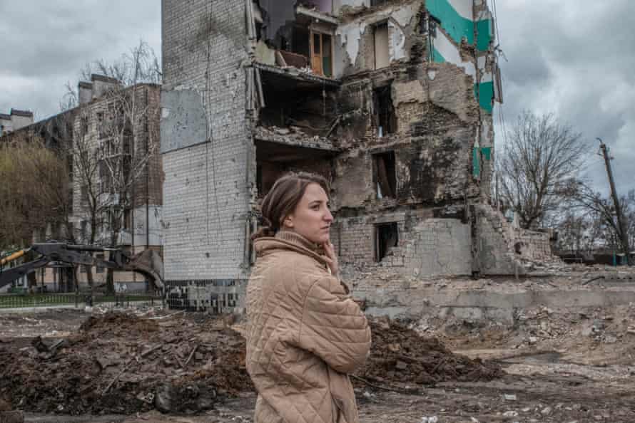 A woman standing in front the rubble of a building in Borodyanka