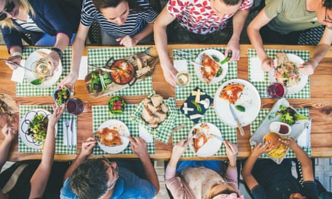 A view from above of a group of friends eating a meal together at a large dining table