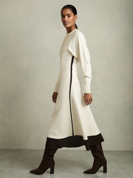 Model wearing a white knitted dress edged in black.