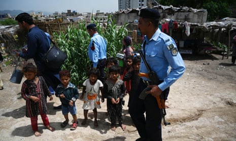 Pakistani policemen escort members of a polio vaccination team during a door-to-door polio immunisation campaign on the outskirts of Islamabad