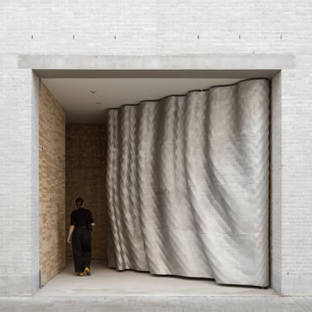 A person walks past a rippling, sculptural entrance gate at Design Museum Ghent
