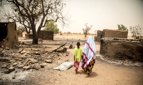 Maïmouna Barry, 45, walks through what is left of the village of Ogossagou-Peulh in Mali, following a recent attack, with her daughter Hawa, 10