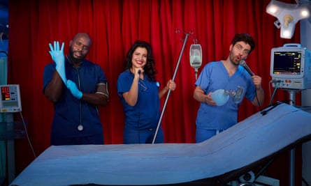 Michael Akadiri, Stefania Licari and Ed Patrick in swabs, standing alongside a medical bed with equipment, making exaggerated, silly faces