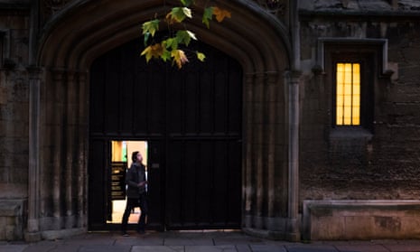 A student in the doorway of a college’s stone gateway