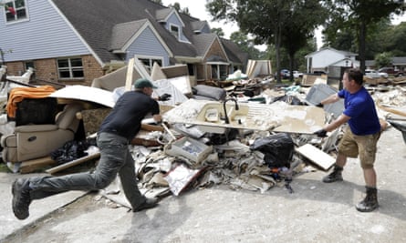 Volunteers Travis Adair, right, and Matt Vinks throw a kitchen sink damaged by flood waters on to a pile of debris.