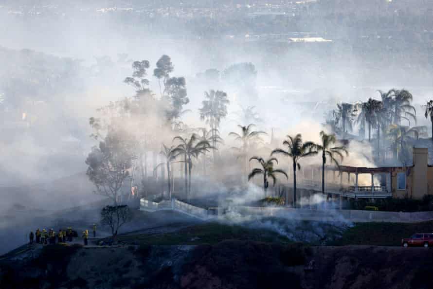 Smoke from a fast-moving, wind-driven wildfire rises above a residential area in Laguna Niguel, California.