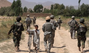 A young Afghan boy walks past Afghan troops and US soldiers in Logar province. 3388.jpg?width=300&quality=85&auto=forma