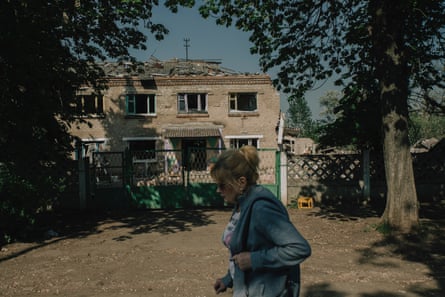 A woman walks in front of a kindergarten whose roof and windows have been destroyed