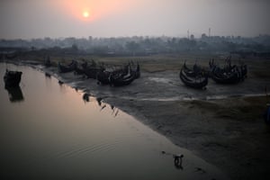Um refugiado Rohingya trabalha na água ao amanhecer ao lado de barcos de pesca no campo de refugiados de Shamlapur
