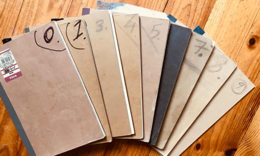A set of brown notebooks fanned out on a wooden floor, with #2 missing