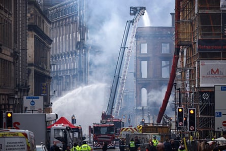 Firefighters outside a historic building with smoke pouring from it.