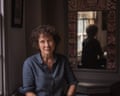 A woman with a curly hair wearing a blue shirt with a mirror behind her