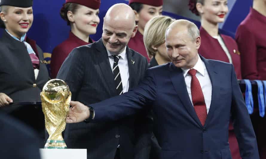 Vladimir Poutine caresse le trophée de la Coupe du monde aux côtés du président de la FIFA Gianni Infantino après la finale de la Coupe du monde 2018