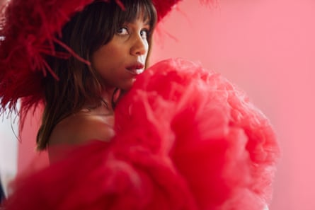 A portrait of Zawe Ashton wearing a red dress and a red ostrich boa hat