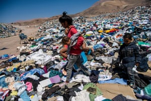 Two people sifting through piles of clothes in Chile’s Atacama desert