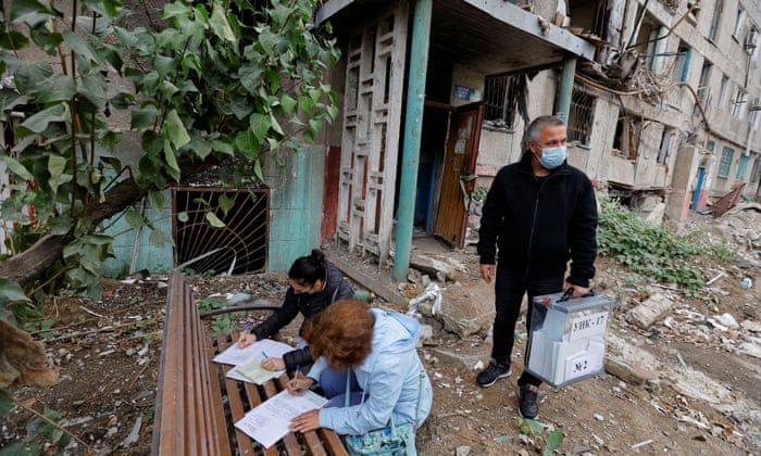 A local resident fills in a document before casting a ballot into a mobile ballot box carried by members of an electoral commission on the second day of a “referendum”.