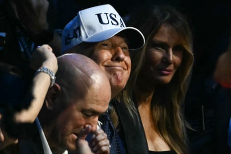 Donald Trump looks on between the First Lady and Dana White.