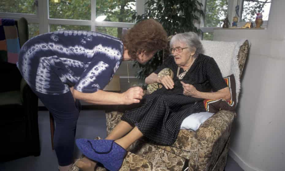 A woman tending to an elderly lady in a care home