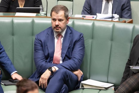 A man in a blue suit sits on a green bench.