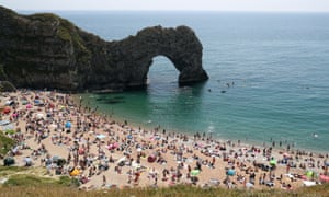 The well-known limestone arch at Durdle Door beach, Dorset – and people enjoying the sand and sea earlier on Saturday.