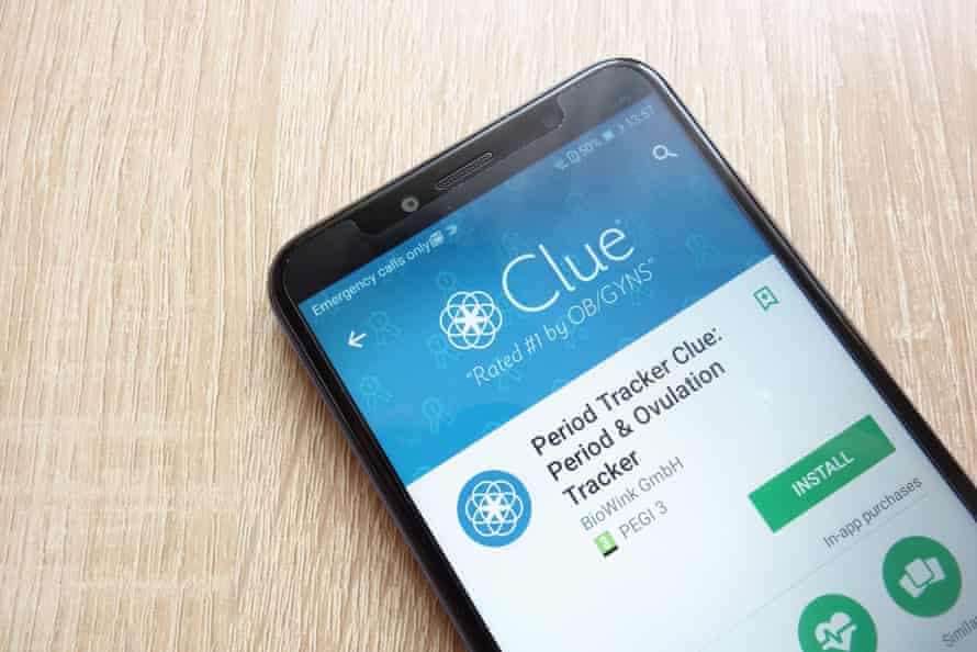A smartphone sits on a light wooden table showing the period tracker app Clue in the Google Play store.