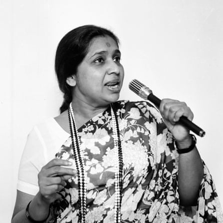 Black and white photo of Asha Bhosle singing into a microphone