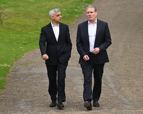 Sadiq Khan and Keir Starmer walk side by side along a path through a park