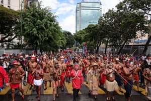 People wearing traditional clothes and holding traditional weapons parade through a city street
