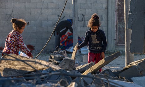 Children walk through rubble in Rafah, southern Gaza, after an Israeli strike