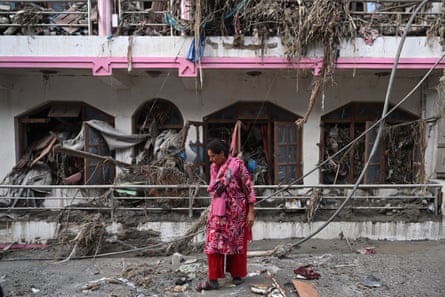 A woman in pink salvages usable materials from her house deluged in sludge following flash floods at Devighat in Nepal’s Nuwakot district