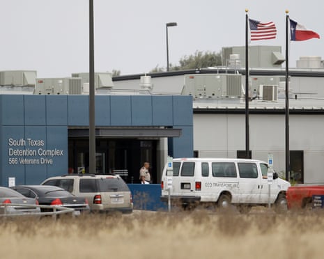 a detention center with a guard and cars parked outside