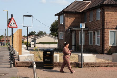 Woman walks in front of redbrick houses and vacant pub