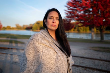 a woman stands outside in front of a body of water and looks ahead