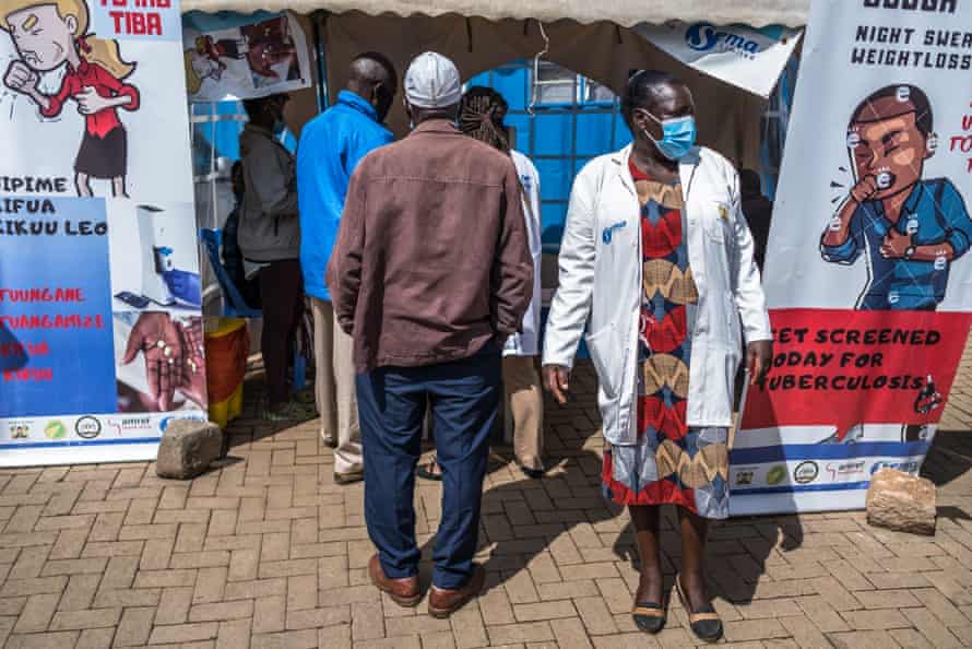 Community health volunteer Violet Chemesunte stands to the right of a queue for TB screening in Kibera.