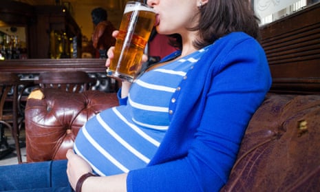 Pregnant woman drinking a pint of beer in pub