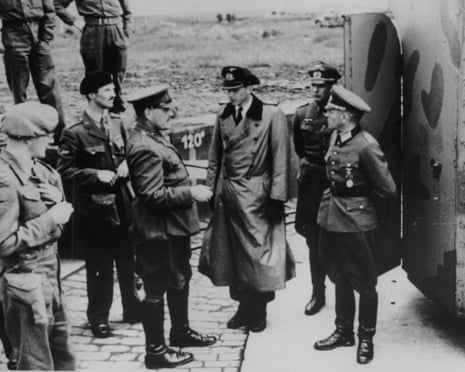 Seven men, some in soldiers' uniforms, watch as Commandant Oberst Schwalm talks to Brigadier Alfred Ernest Snow, surrendering on Alderney on 16 May 1945 next to a metal bunker with an open door
