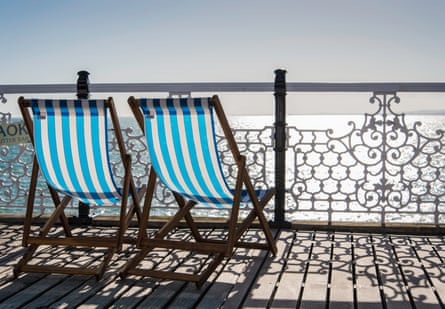 Two blue striped deck chairs on Brighton pier, overlooking the sea on a sunny day